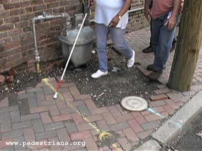 Blind pedestrian crossing broken sidewalk section.