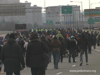 Pedestrians fill a major highway bridge