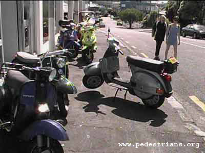 Motor scooters block the sidewalk.