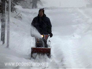 Snow blower clearing sidewalk.