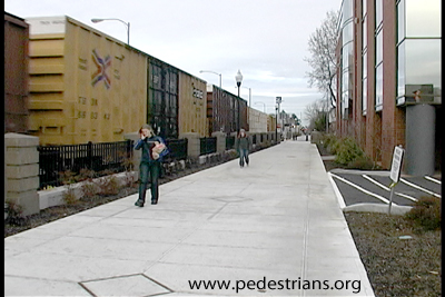 photo - pedestrians on walkwway next to train.